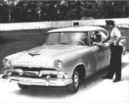 Black and White photo of Police car standing next to early police car